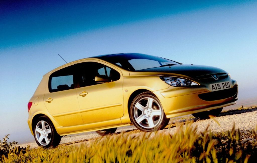 Side view of a gold Peugeot 307 parked on a gravel track