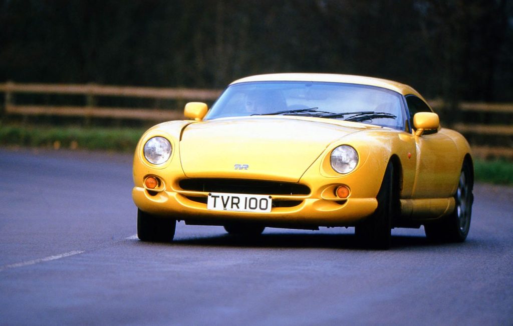 Man driving a yellow TVR Cerbera along a road