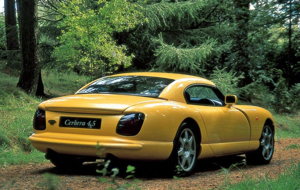 Rear view of a yellow TVR Cerbera parked in a forest surrounded by trees