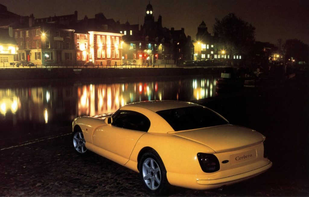 Yellow TVR Cerbera parked at the side of a river at night time