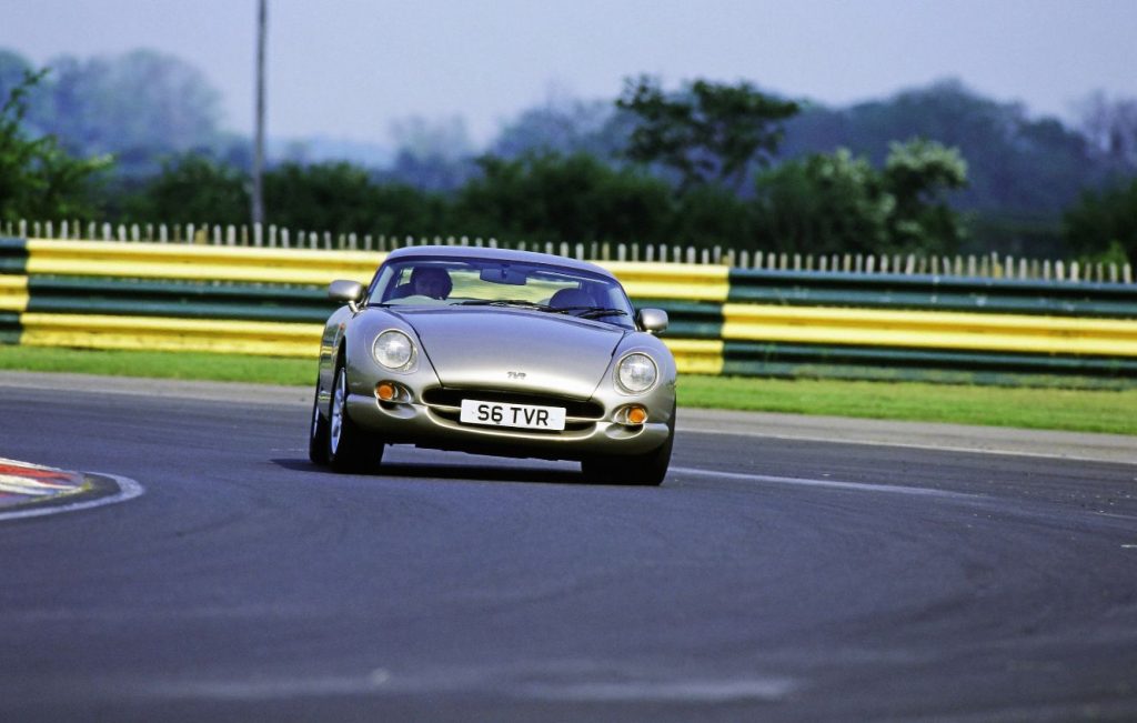 Man driving gold TVR classic car around a bend of a race track