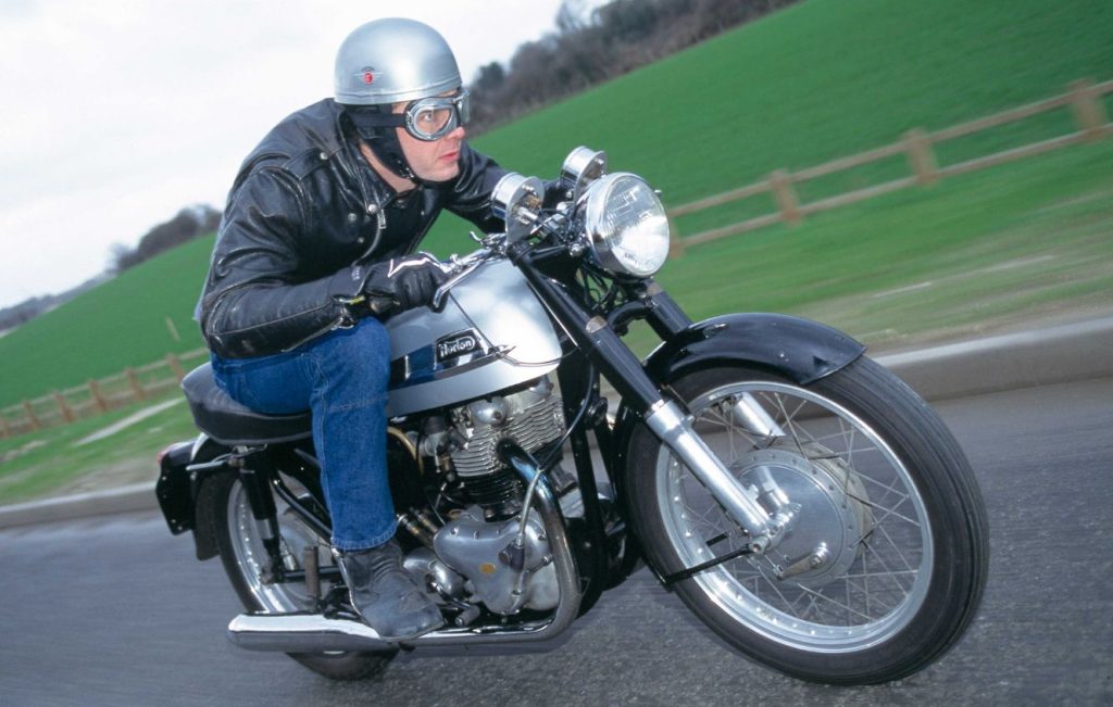 Man riding Norton Dominator 88 motorcycle along a road
