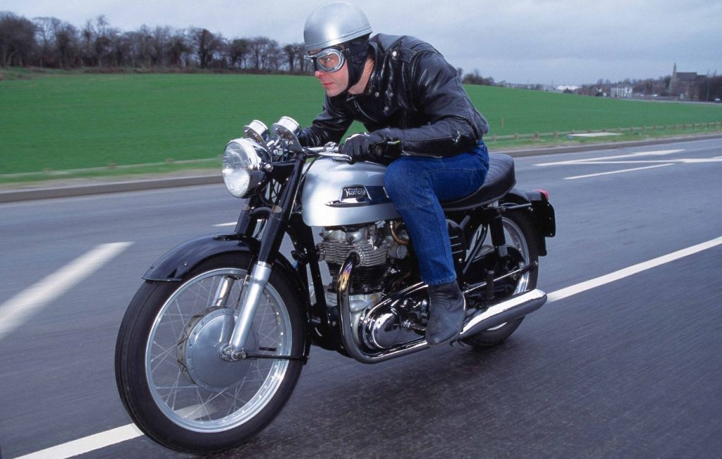 Man riding Norton Dominator 88 motorcycle along a road