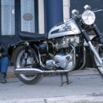 Man sat next to a black and chrome classic motorbike