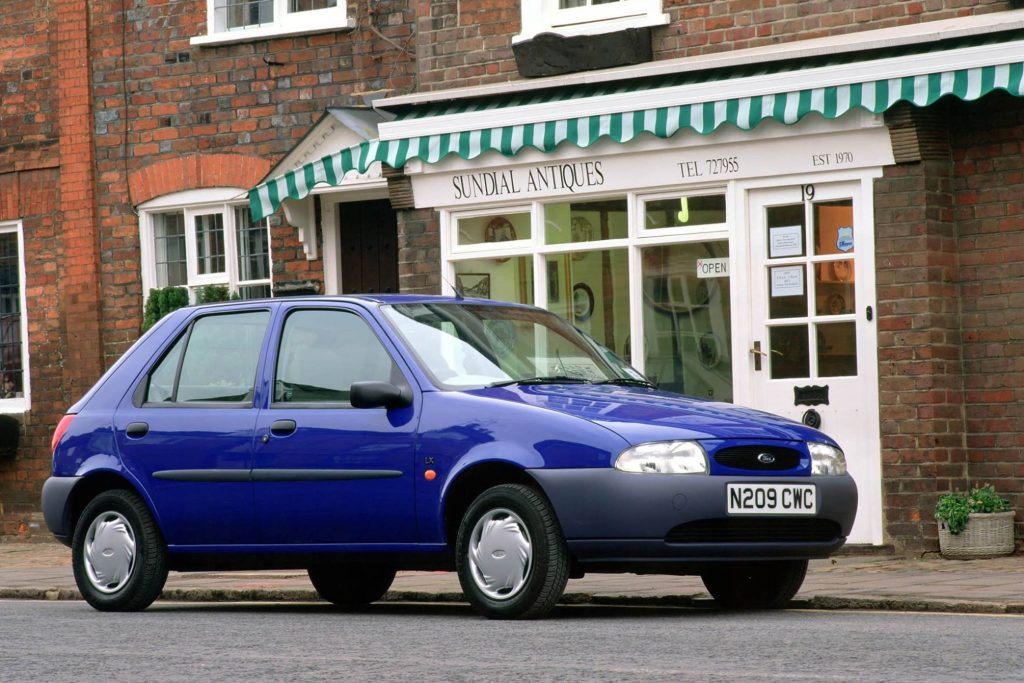 Blue Mk4 Ford Fiesta five-door hatchback parked on a cobbled street outside Sundial Antiques shop