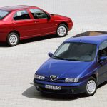 Blue Alfa Romeo 145 three-door hatchback and red Alfa Romeo 146 saloon photographed from above on a cobbled surface