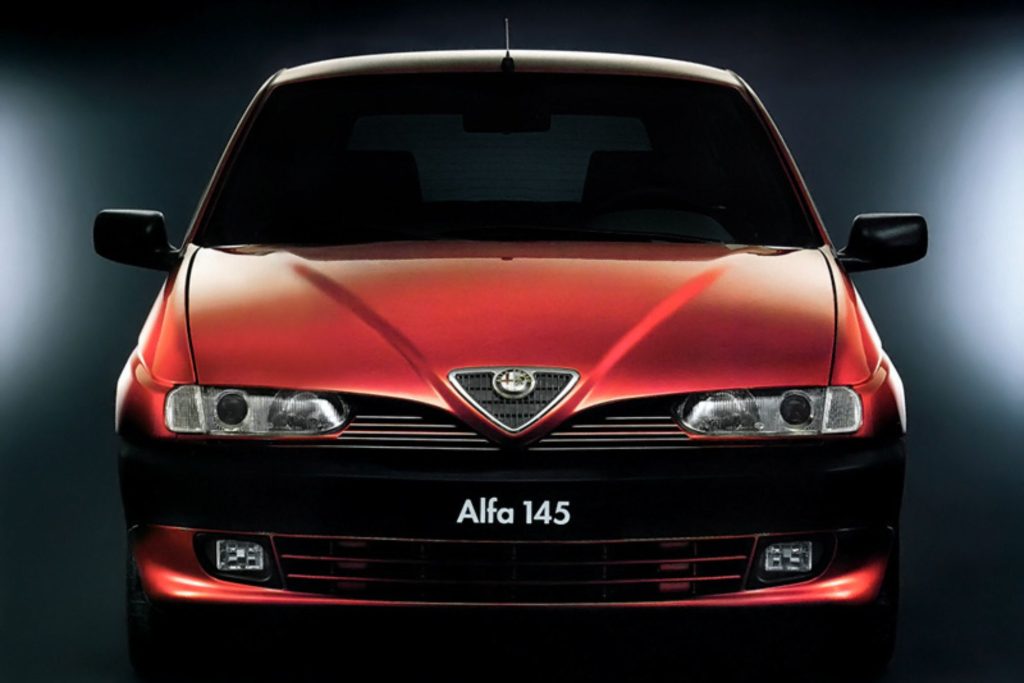 Front-on studio press photo of a dark red Alfa Romeo 145 showing the Alfa Romeo badge and twin headlights