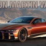 A copper-colored Aston Martin Valen sports car parked in front of a mountain landscape, with a man standing beside the driver's door. Large text across the top reads “ASTON MARTIN VALEN.”