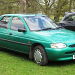 Green Mk6 Ford Escort five-door hatchback parked on grass at a car show with trees in the background