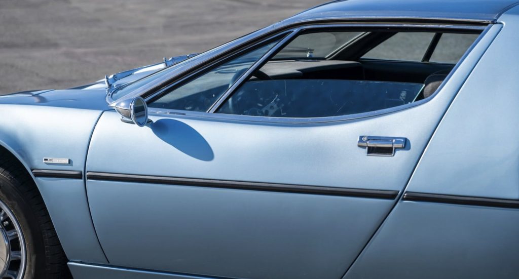 Close-up of the driver's side door and greenhouse area of a light blue metallic Maserati Bora