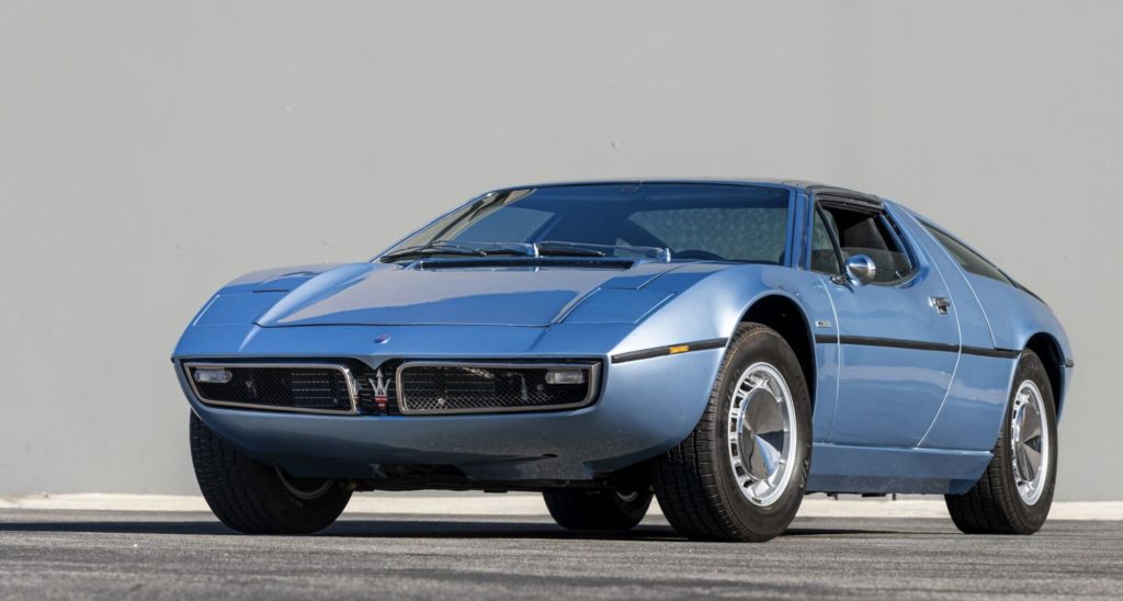 Low-angle front three-quarter view of a light blue Maserati Bora emphasizing the wedge nose