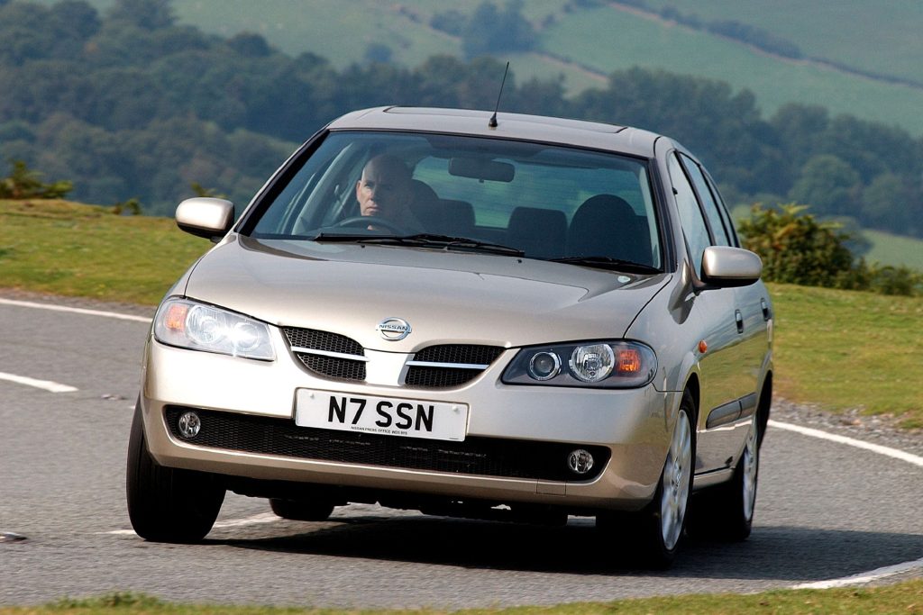 Gold Nissan Almera N16 five-door hatchback on a country road, front three-quarter view