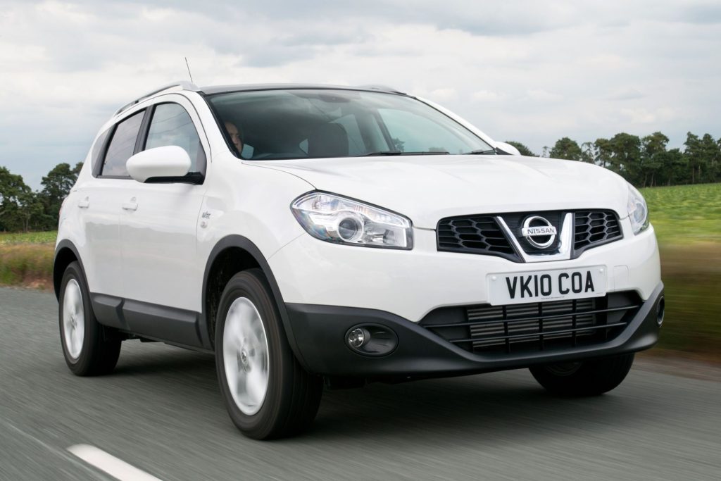 White Nissan Qashqai J10 crossover SUV driving on a country road, front three-quarter view
