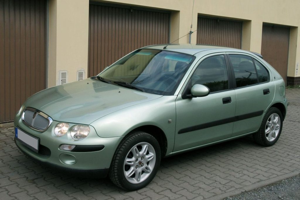 Silver-green Rover 25 five-door hatchback parked on a cobbled driveway in front of a row of garages