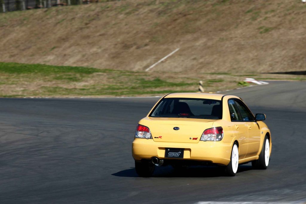 2006 Subaru Impreza WRX STI S204 RA-R Lemon Yellow rear view cornering on racetrack showing STI badge and white wheels
