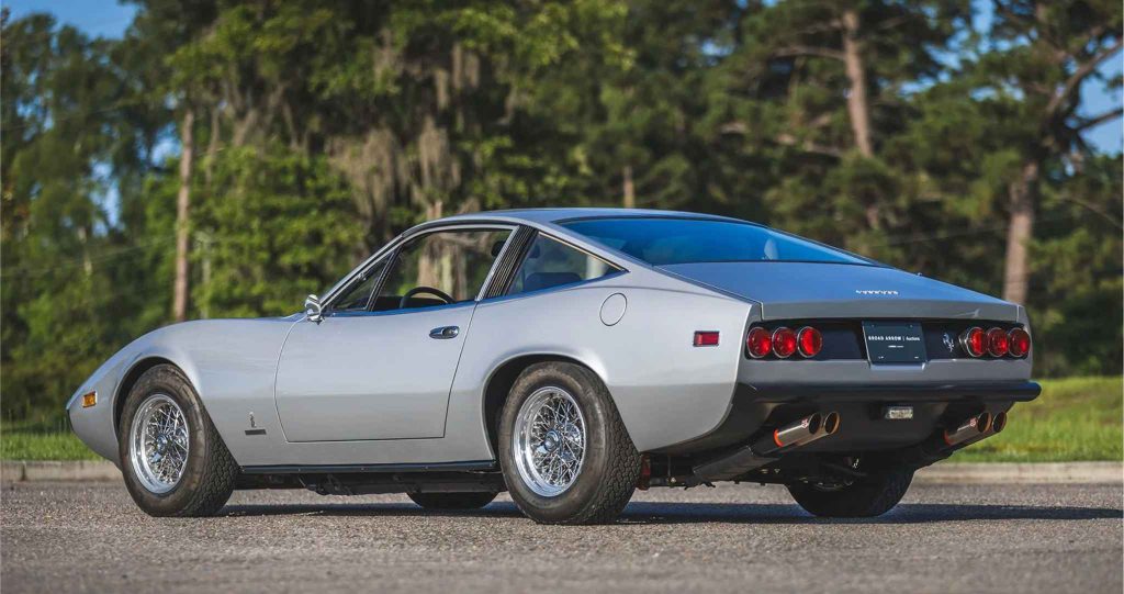 Rear three-quarter view of a silver Ferrari 365 GTC/4 showing the fastback roofline, quad round taillights, dual exhaust pipes, and wire-spoke wheels