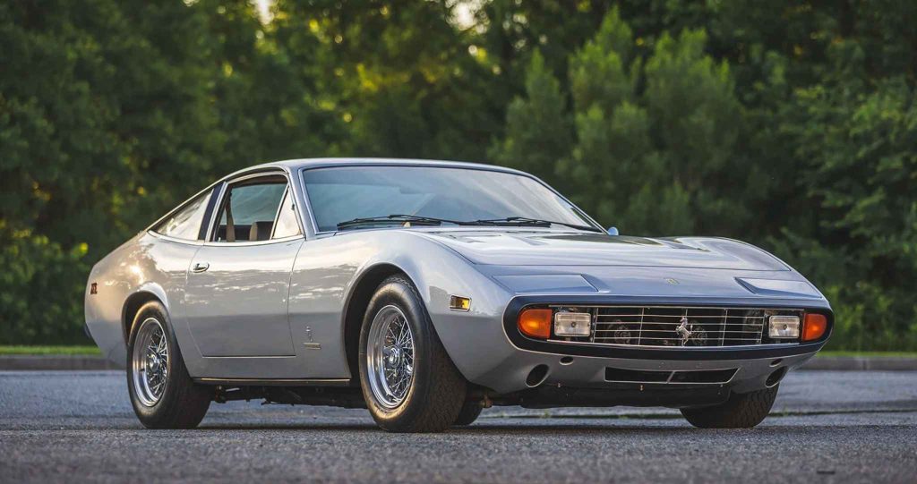 Silver Ferrari 365 GTC/4 at golden hour, three-quarter front view showing the distinctive wide nose, amber headlight surrounds, and prancing horse grille badge