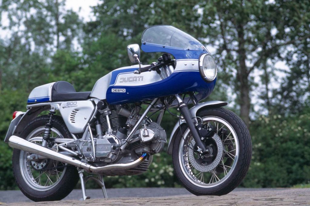 Ducati 900 Super Sport in blue and white Desmo livery, low three-quarter front view showing the half-fairing, clip-on bars and desmodromic V-twin engine
