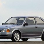 A silver-grey Ford Escort RS Turbo three-door hatchback photographed in a three-quarter front view against a pale sky, with a German licence plate reading K-FO 287