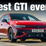 Red Volkswagen Golf GTI Edition 50 driving on a road, photographed from a low front three-quarter angle.