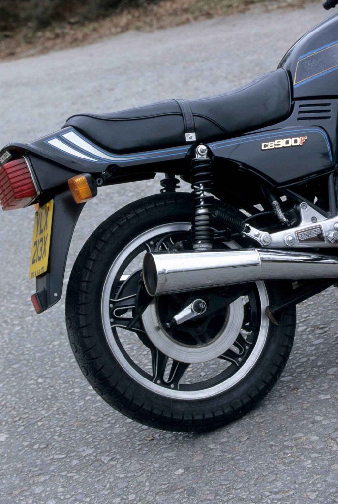 Rear quarter view of the Honda CB900F showing the taillight, rear indicators, UK license plate (YLX 213X), chrome exhaust can, dual shock absorbers, and black ComStar rear wheel.