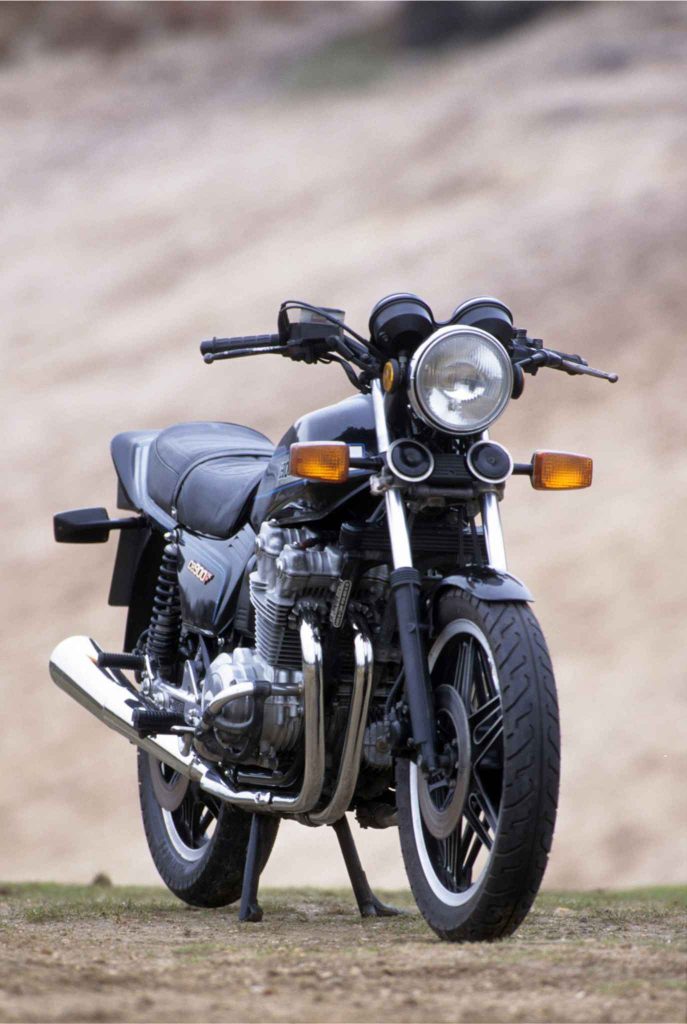 Head-on front view of the Honda CB900F on its center stand, showing the round headlight, dual instrument pods, wide handlebar, and the full four-into-four exhaust system sweeping forward.