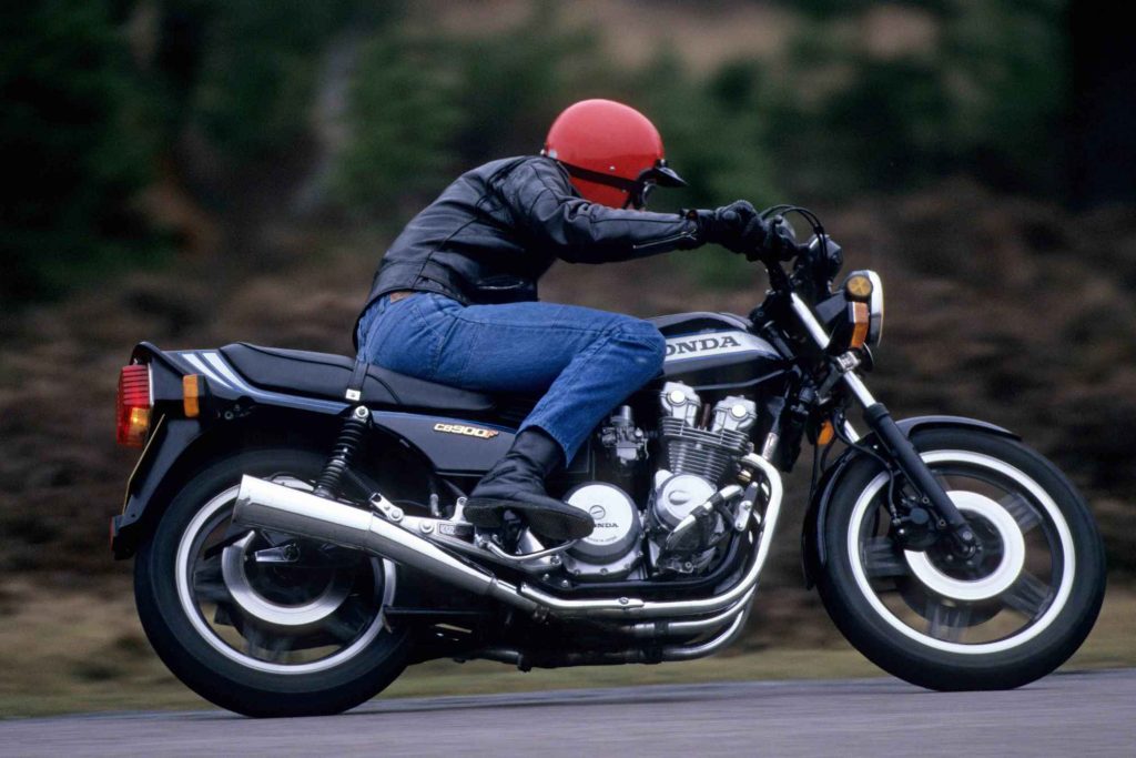 Rear three-quarter action shot emphasizing the Honda CB900F's tail section, CB900F badge on the side panel, and the chrome megaphone-style exhaust collector.