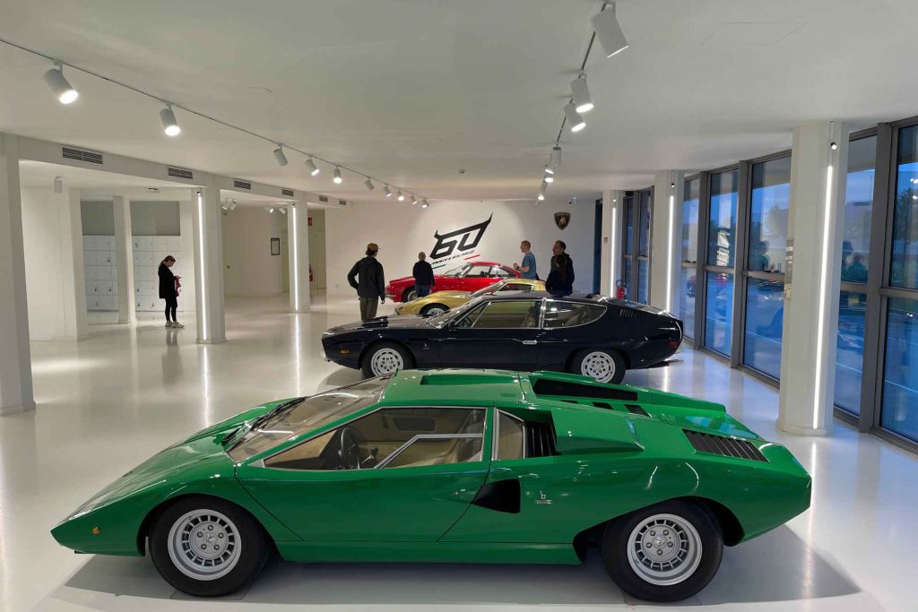 The Lamborghini Museum showroom featuring a green Countach LP400 in the foreground, a dark blue Espada behind it, and additional classic models