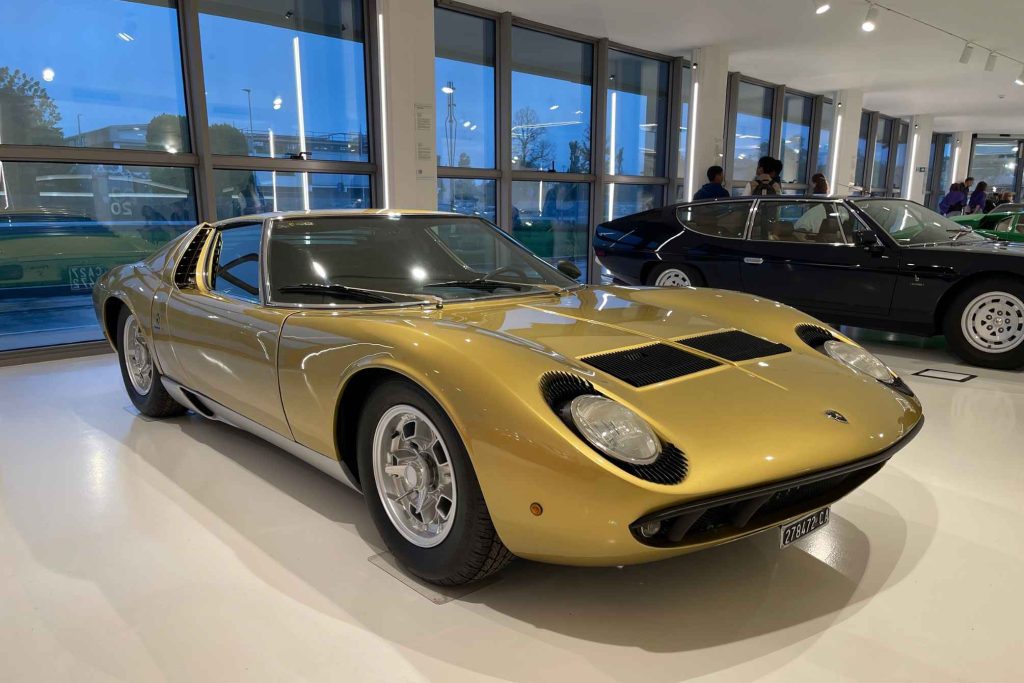 A gold Lamborghini Miura displayed in a museum showroom