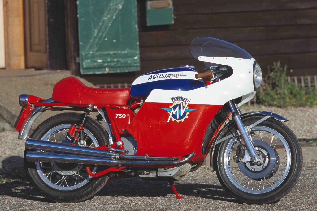 MV Agusta 750 Sport in red and white race livery being ridden at speed, rider in black leathers and red open-face helmet, MV Agusta badge prominent on the fairing