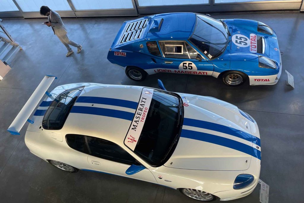 Overhead view of two blue-and-white racing Maseratis displayed in a museum