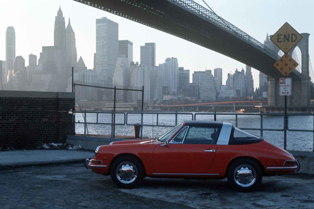 Red Porsche 911 Targa parked beneath the Brooklyn Bridge with the Manhattan skyline in the background