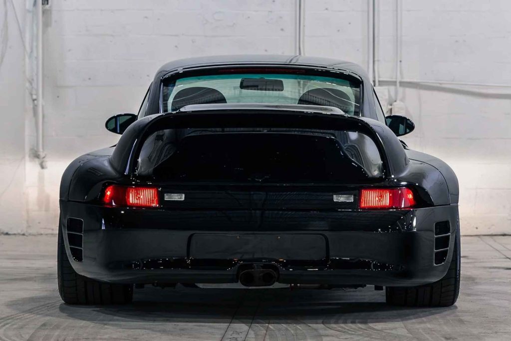 Dead-on rear view of the black Ruf CTR2 Sport, showing the full-width tail light bar, twin exhaust outlet, wide rear bumper with twin air vents, and the steeply raked rear screen above the engine lid.