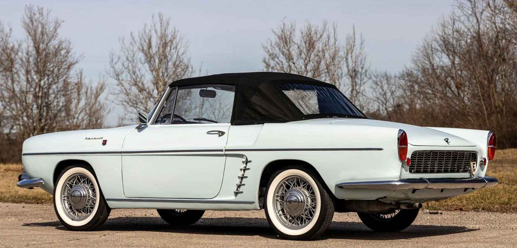 Rear three-quarter view of the Renault Floride cabriolet with its black soft top raised, showing the distinctive rear grille, round tail lights, chrome bumper, and wire wheels with whitewalls.