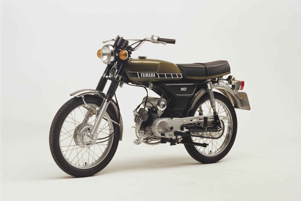 Yamaha FS1-E in olive green, clean studio shot on a white background showing the 50cc two-stroke moped in its post-1977 restricted form, badged simply as Yamaha 50