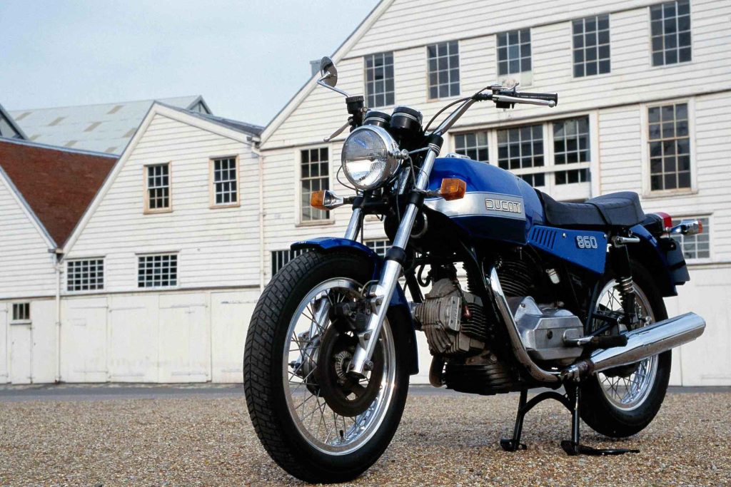Blue and silver Ducati 860 vintage motorcycle parked in front of a white building
