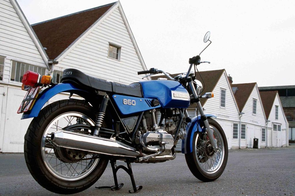 Blue and silver Ducati 860 vintage motorcycle parked in front of a white building