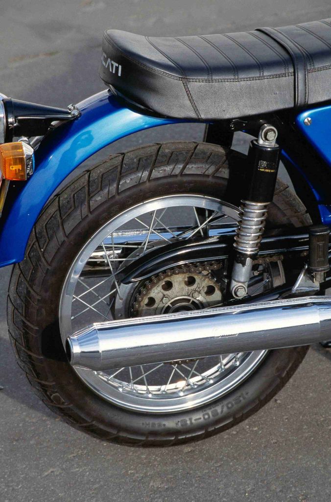 Rear wheel of a Ducati 860 with chrome shock absorber, chain sprocket and chrome exhaust