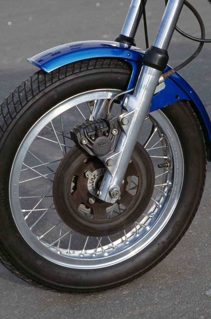 Front wheel of a blue vintage Ducati 860 with spoked rim, Brembo disc brake and caliper