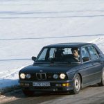Dark blue BMW M535i E28 five-series saloon being driven on a snow-covered winter road