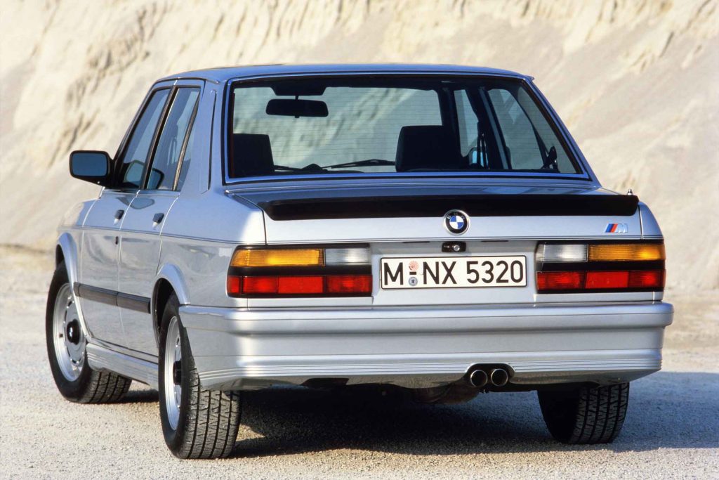 Rear view of a silver BMW M535i E28 five-series saloon parked against a sand dune