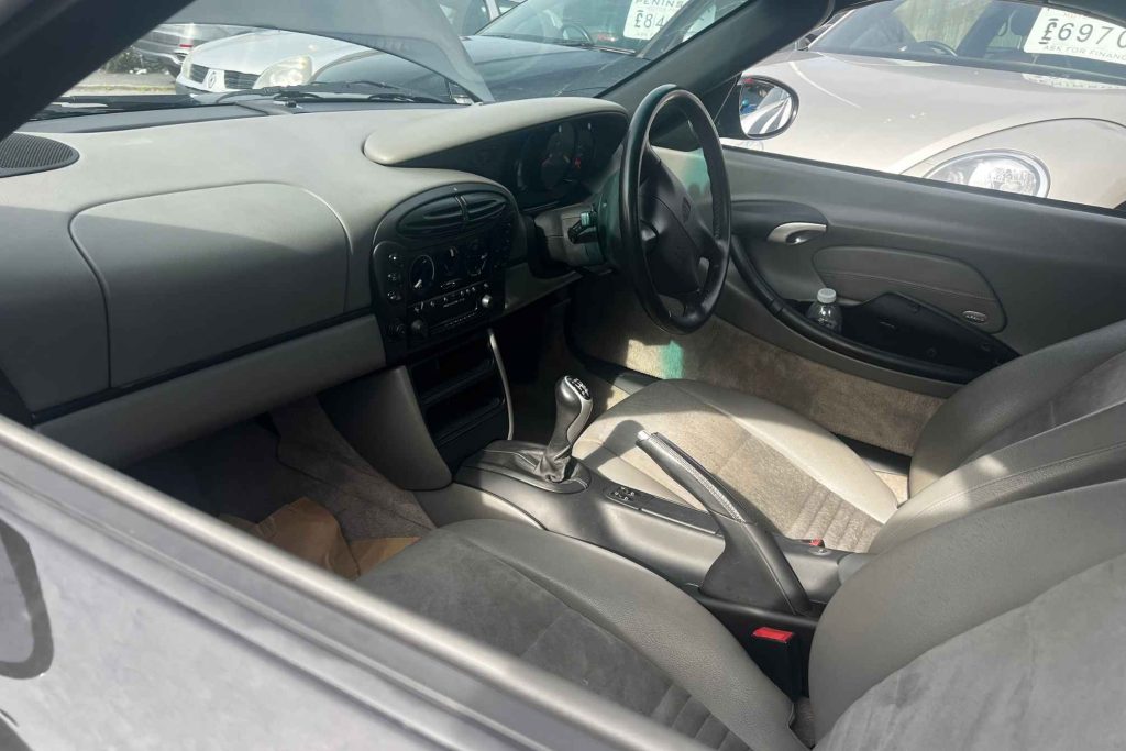 Interior of a Porsche Boxster 986 viewed from the passenger side showing grey two-tone leather seats