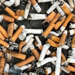 Large pile of cigarette butts and ash covering a surface