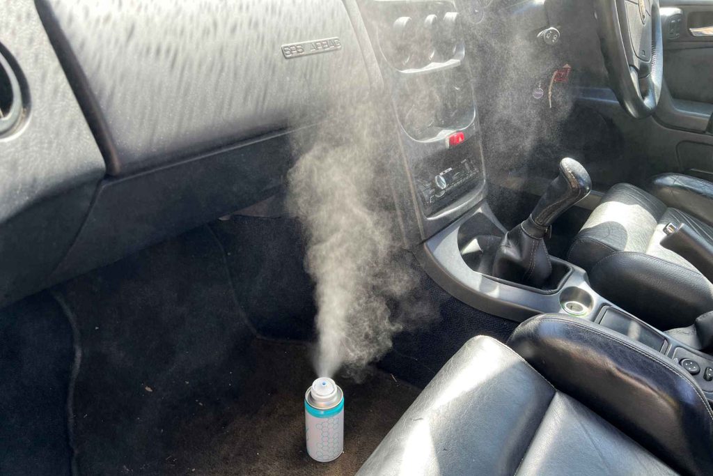 Carbon Collective air conditioning refresh spray being used inside a car interior to eliminate cigarette smoke smell