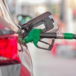 Green fuel nozzle refuelling a red car at a petrol station