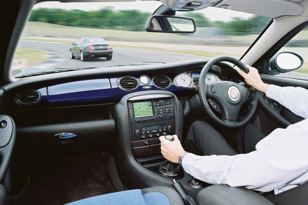MG ZT V8 interior showing dashboard, navigation system and gear lever with driver at wheel