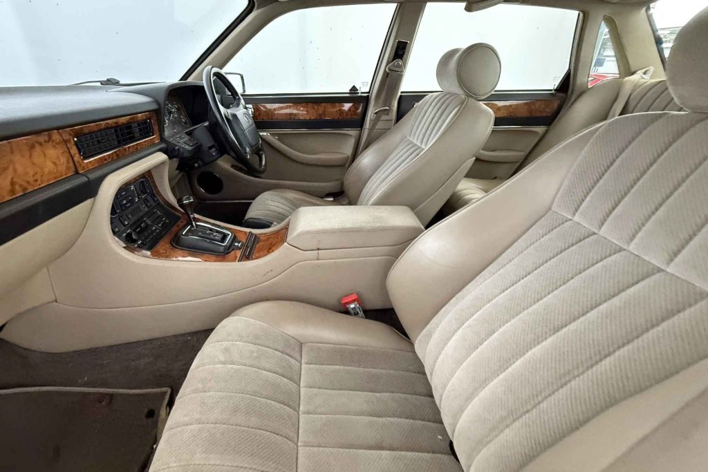 Interior of a Jaguar XJ6 Series III showing cream velour front and rear seats and burr walnut dashboard