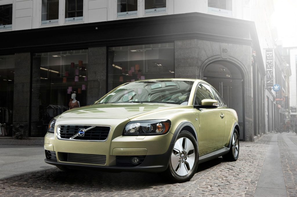 Green Volvo C30 DRIVe parked on a cobblestone street in the city