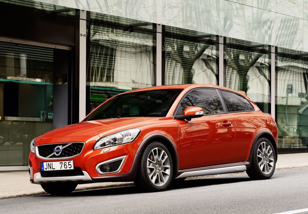 Orange facelifted Volvo C30 with silver lower trim parked beside a glass building